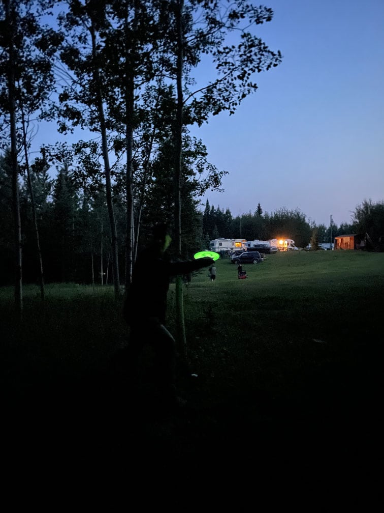 A disc golfer throwing a glow disc from the fairway